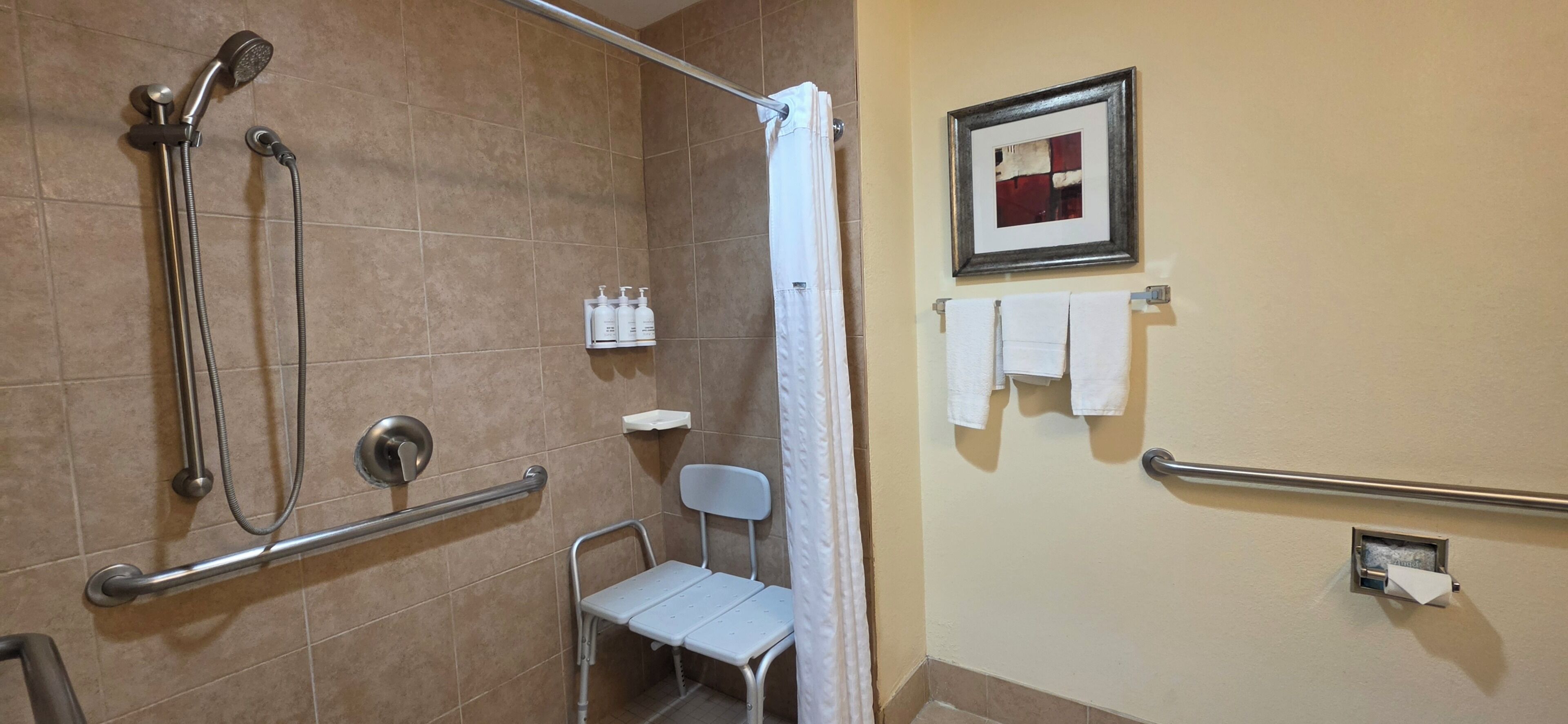 A shower area with a grab bar, a chair, and a towel rack.