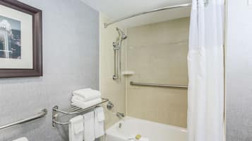 Un baño moderno con bañera, ducha y barras de apoyo.