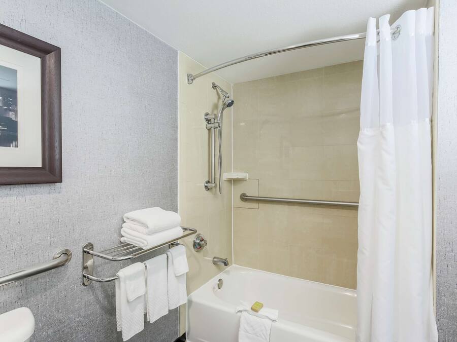 Un baño moderno con bañera, ducha y barras de apoyo.