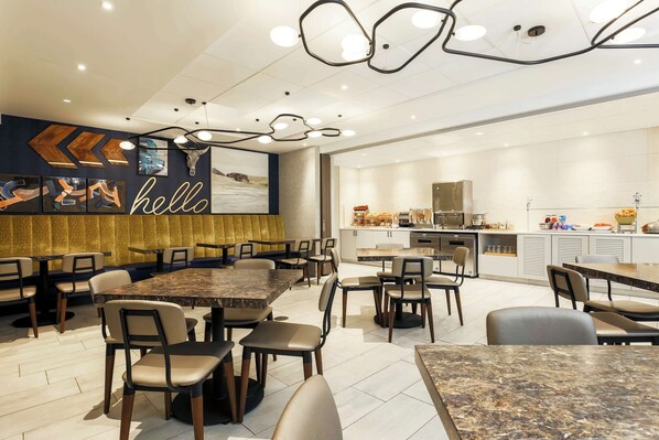 A modern restaurant with multiple dining tables and chairs, a kitchen area, and a 'hello' sign on the wall.
