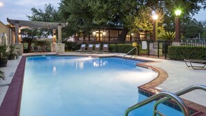 A swimming pool with a pergola, lounge chairs, and a fence. - DoubleTree by Hilton Austin - University Area (Austin)