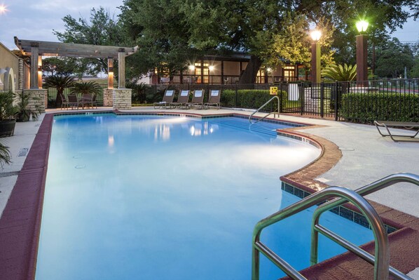 Una piscina al aire libre, sillones reclinables de piscina