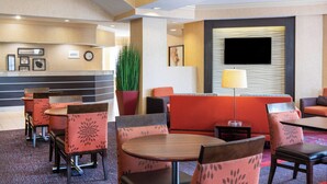 Vestíbulo de hotel con zonas de estar, mostrador de recepción y pantalla de televisión.