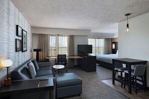 A modern hotel room with a sofa, desk, TV, and dining area. - Residence Inn by Marriott Evansville East (Evansville)