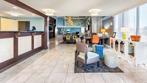 Een hotel lobby met een receptiebalie, een zithoek en een keuken op de achtergrond.