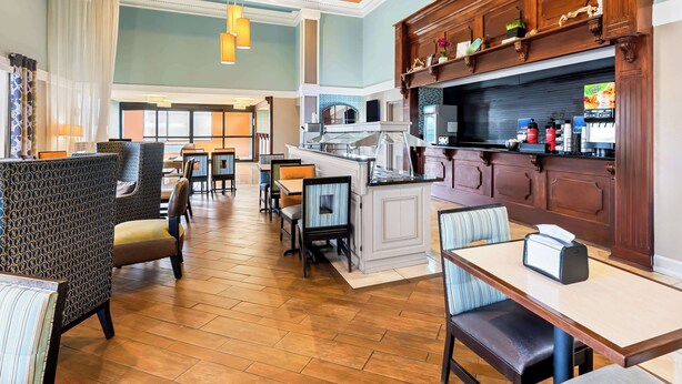 Een ruime hotellobby met een centraal gelegen bar, zitgedeeltes en uitzicht op de eetruimte.