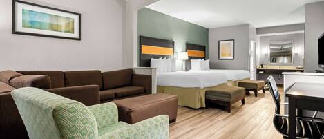 A hotel room with a bed, a sofa, a chair, a desk, and a mirror.