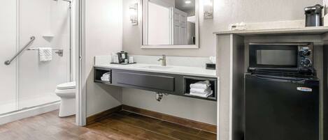 A modern bathroom with a shower, toilet, sink, and a built-in microwave.