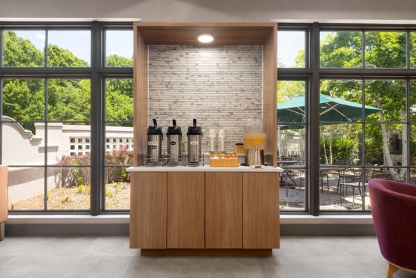 A modern kitchen with a built-in espresso machine, a coffee station, and a view of the outdoor patio through large windows.
