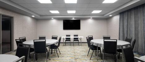 A conference room with a carpeted floor, round tables, and chairs.