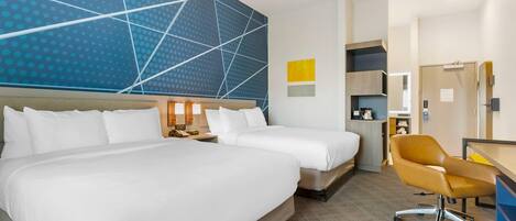 Ein Hotelzimmer mit zwei Betten, einem Schreibtisch, einem Stuhl und einer Wand mit großem geometrischem Muster.