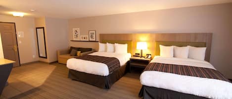 A hotel room with two beds, a desk, a chair, and a small sofa.