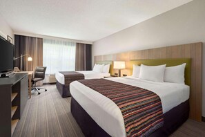 A hotel room with two beds, a desk, a chair, a TV, and a large window with curtains.