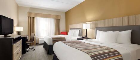 A hotel room with two beds, a desk with a television, a chair, and a window with curtains.