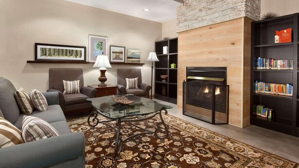 A living room with a fireplace, sofas, a coffee table, and a bookshelf.