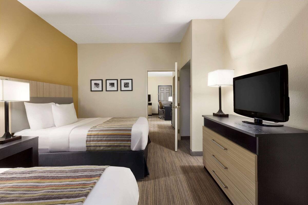 Habitación de hotel con dos camas, televisión, escritorio y una silla.