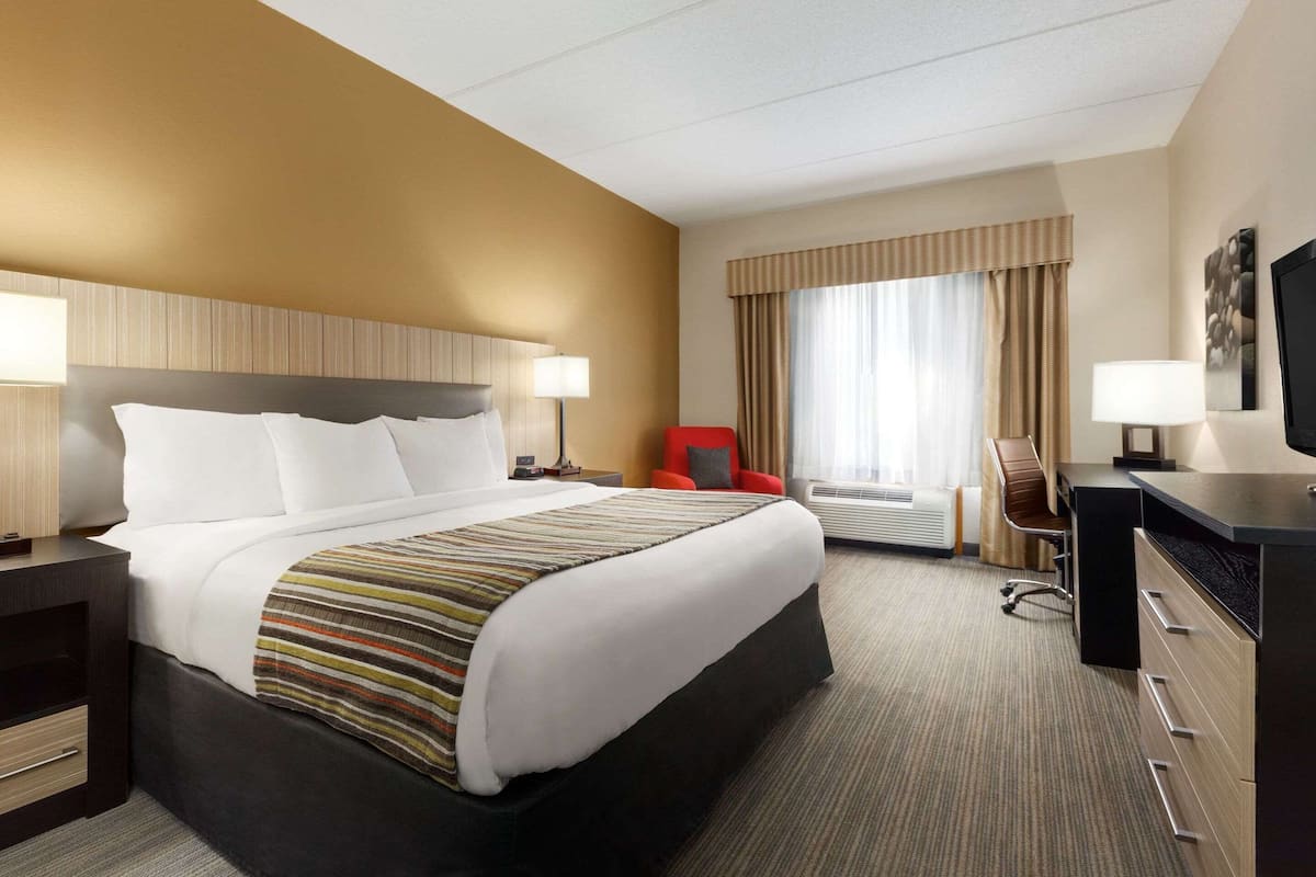 Una habitación de hotel con una cama grande, un escritorio, una silla y un televisor.