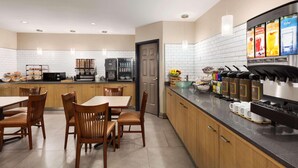 A modern kitchen with a coffee station, wooden chairs, and a tiled backsplash.