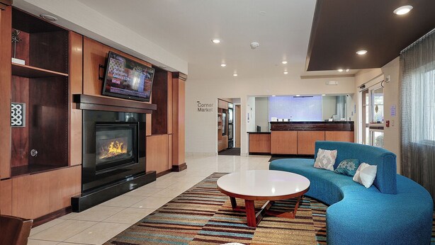 A modern living room with a fireplace, a television, and a blue sofa. - Sonesta Essential Houston Energy Corridor (Houston)