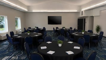 A conference room with multiple tables, chairs, and a flat-screen TV on the wall.