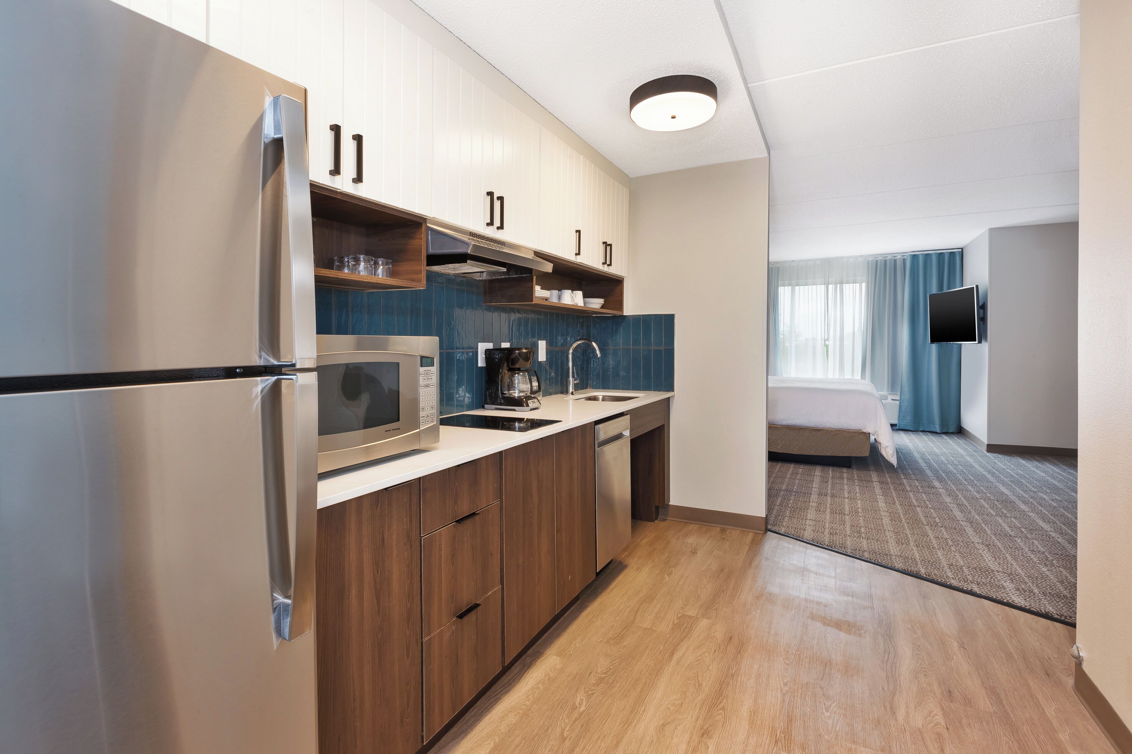 A compact hotel kitchen with a refrigerator, microwave, coffee maker, and a sink.