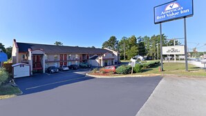 Un motel avec un panneau indicateur, un espace de stationnement et un petit jardin.