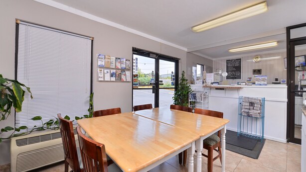 Une pièce propre et bien éclairée, avec une table et des chaises en bois, un petit coin cuisine et une vue sur l’extérieur, visible à travers la porte.