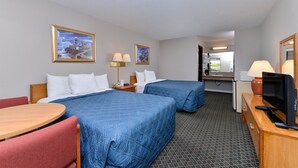 Une chambre d’hôtel avec deux lits, un bureau avec une télévision, une chaise, une lampe et un tableau au mur.