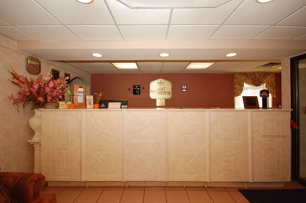 A reception desk with a clock, a sign reading "Best Western," and a vase of flowers.