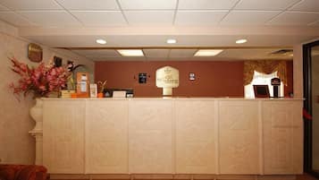 A reception desk with a clock, a sign reading "Best Western," and a vase of flowers.