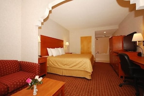 A hotel room with a bed, a sofa, a desk, a chair, a TV, and a bathroom door. - Baymont by Wyndham Franklin (Franklin)