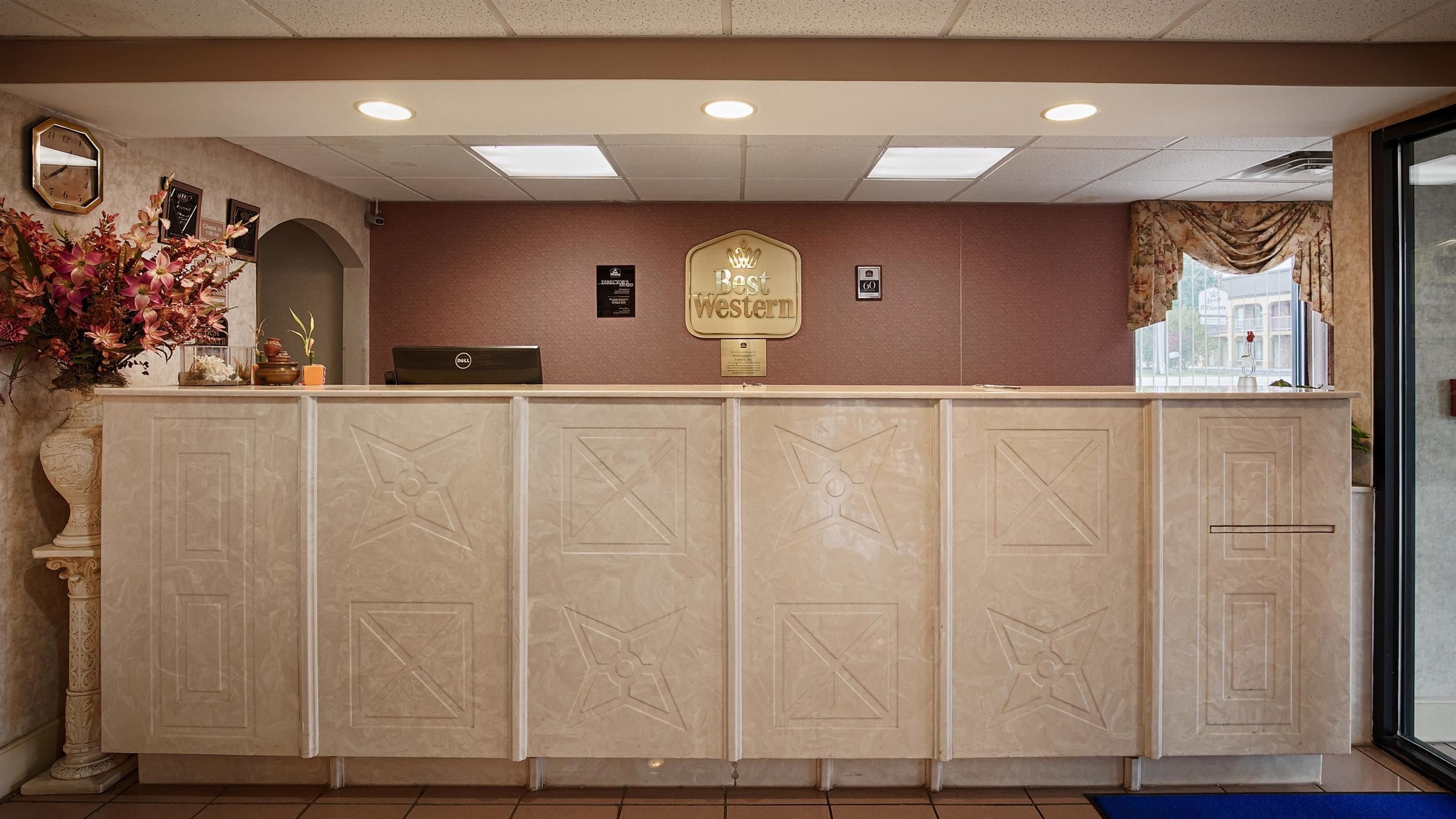 Una mesa de recepción con un letrero que dice "Best Western", un reloj y una computadora Dell.
