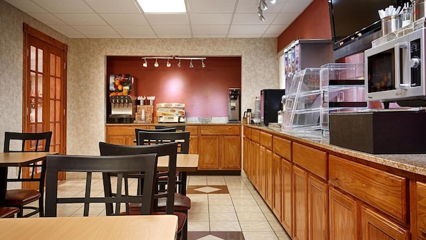 A restaurant with wooden furniture, a coffee machine, and a counter with a microwave.