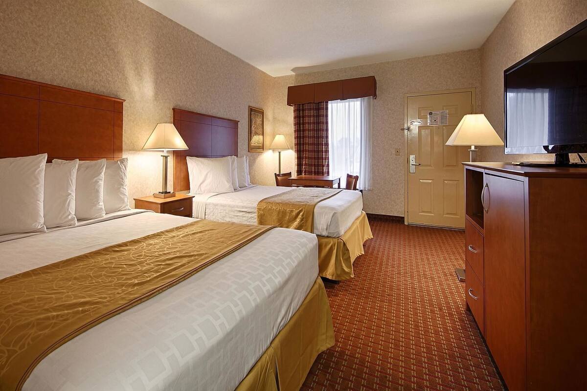 Une chambre d’hôtel avec deux lits, un bureau, une télévision et une porte avec une pancarte.
