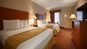 A hotel room with two beds, a desk, a television, and a wardrobe.
