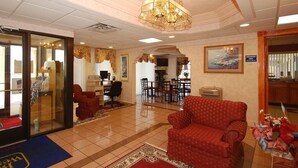 A hotel lobby with a red sofa, a chandelier, a dining area, and a reception desk.
