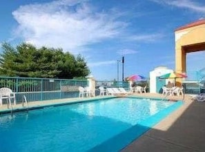 A swimming pool with lounge chairs and umbrellas, surrounded by a fence and trees. - Baymont by Wyndham Franklin (Franklin)
