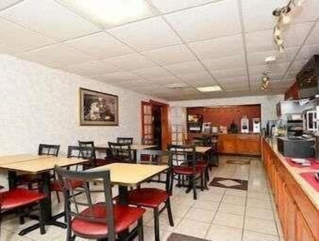 Ein Restaurant mit Tischen, Stühlen, einer Theke und einem Bild an der Wand.