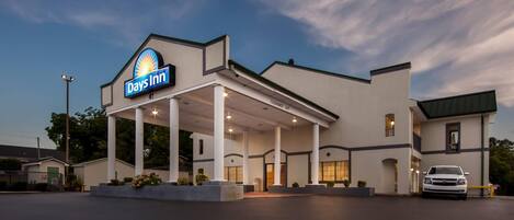 A Days Inn with a covered outdoor area, a car parked in front, and a clear sky.