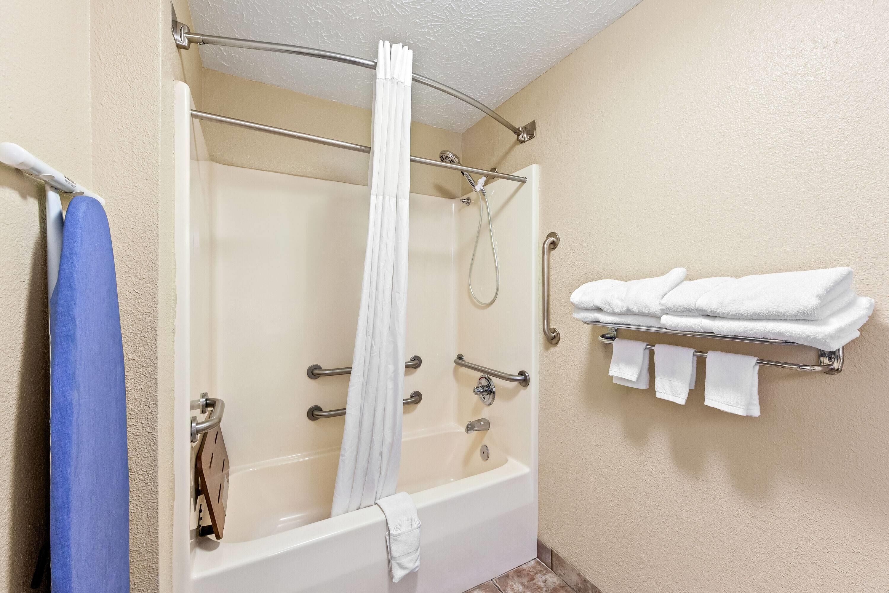 A bathroom with a bathtub, a shower, and a towel rack with towels.