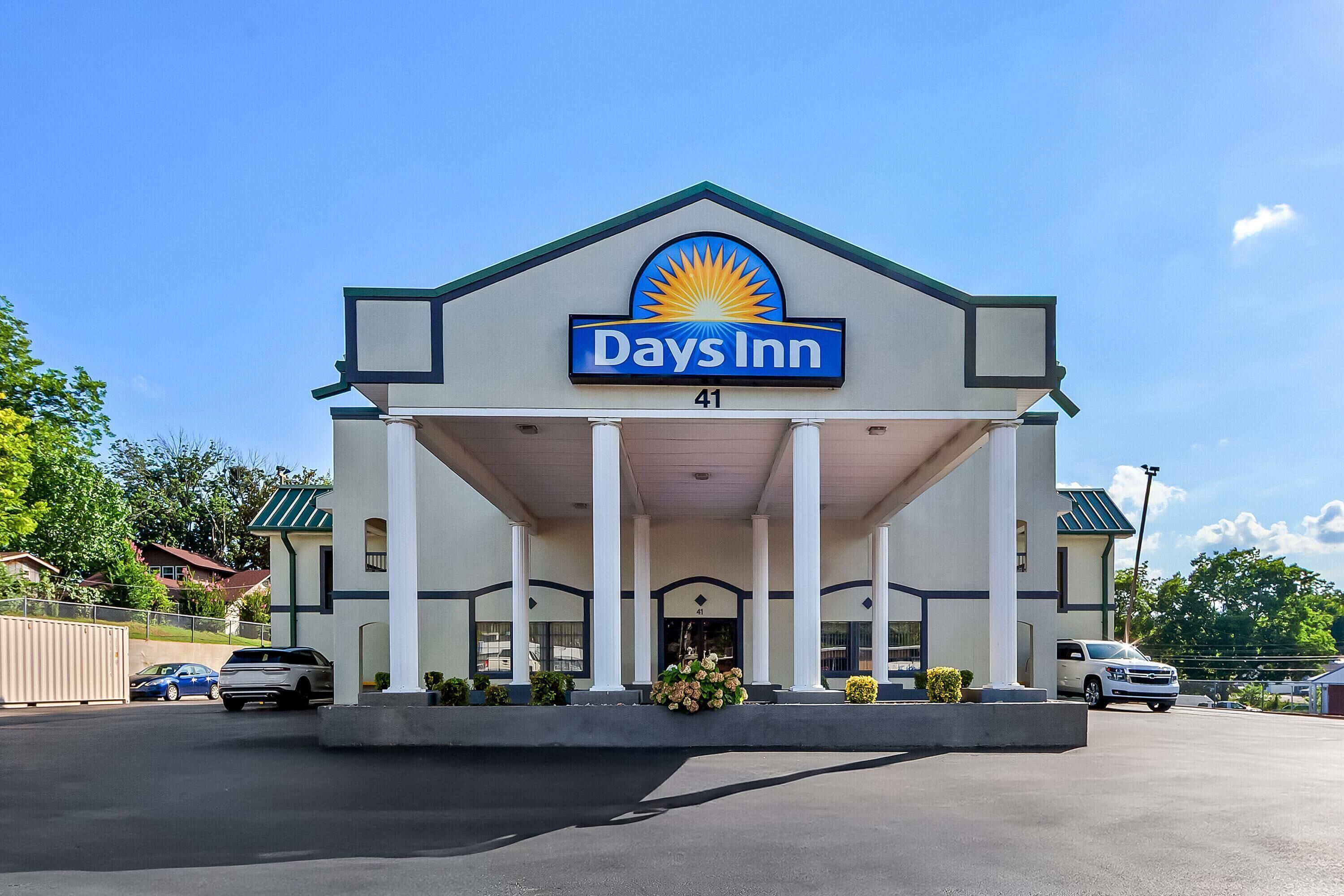 Edificio de Days Inn con un llamativo logo de sol, entrada cubierta con columnas y un cartel con el número 41.
