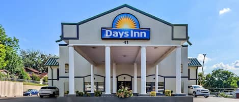 Edificio de Days Inn con un llamativo logo de sol, entrada cubierta con columnas y un cartel con el número 41.