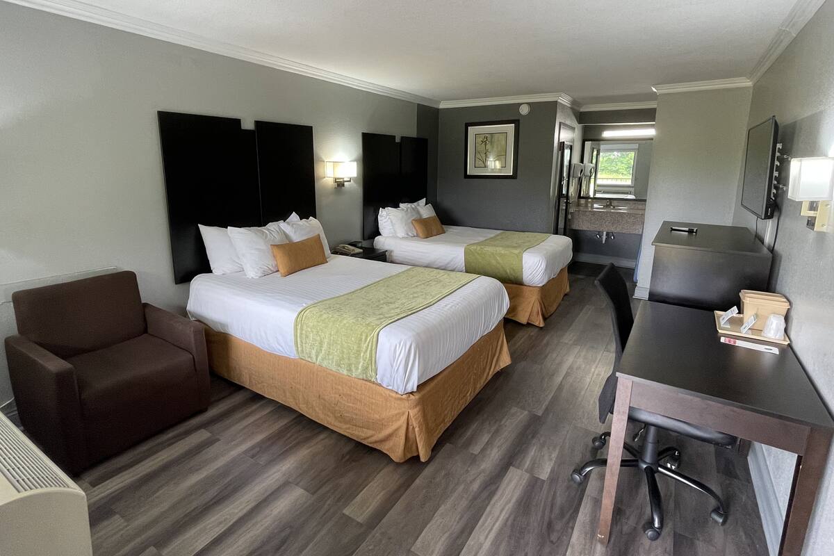 Une chambre d’hôtel avec deux lits, un bureau, une chaise et un petit canapé.