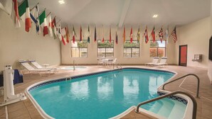An indoor swimming pool with multiple flags, lounge chairs, and a tiled floor. - Radisson Hotel and Conference Center Rockford (Rockford)