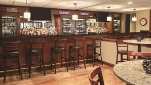 A bar area with wooden bar stools, a marble-topped table, and a clock on the wall. - Radisson Hotel and Conference Center Rockford (Rockford)