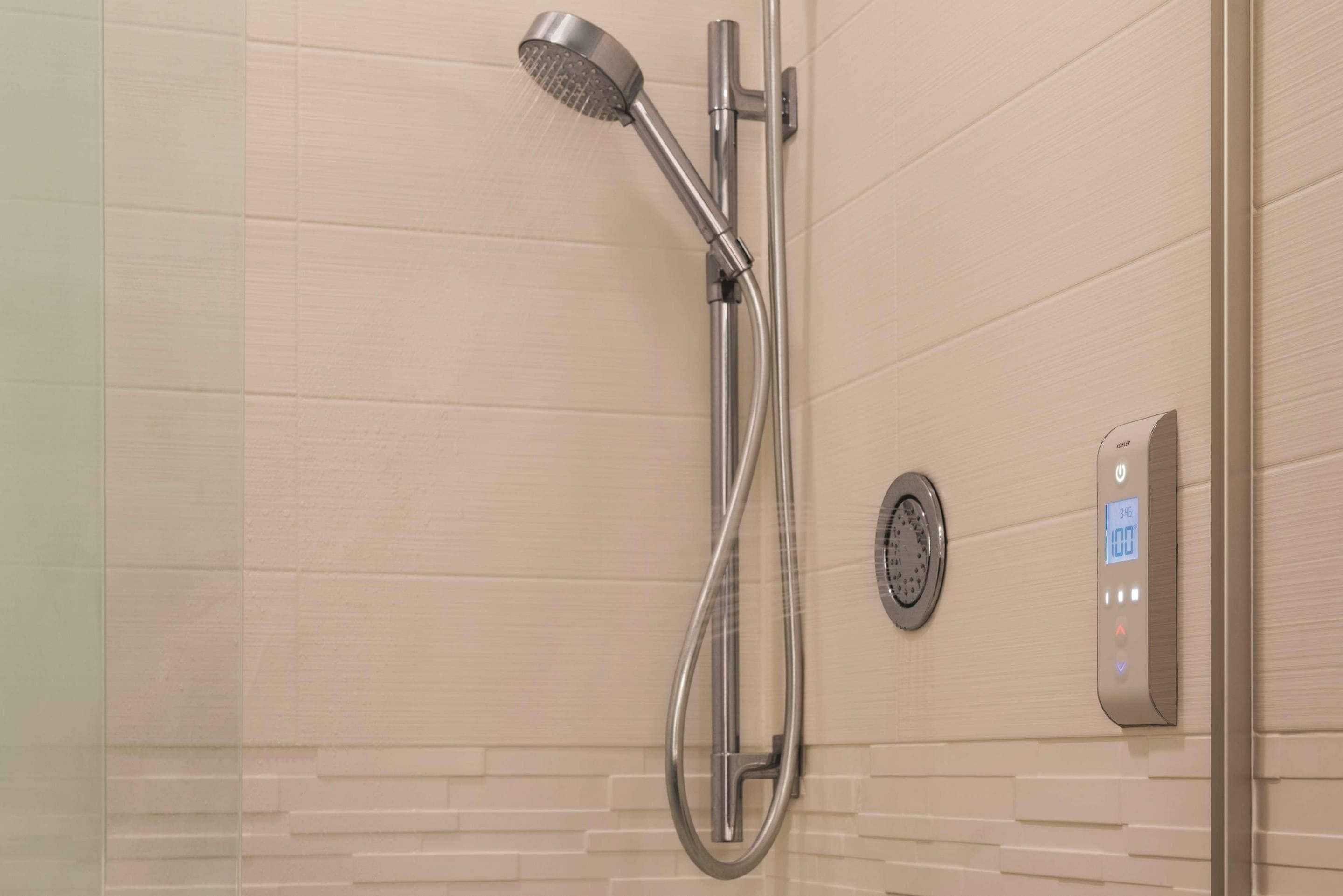 Une douche moderne dotée d’un panneau de commande numérique et d’un pommeau de douche à main.