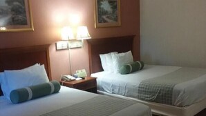 A hotel room with two beds, a nightstand, and wall-mounted lamps.