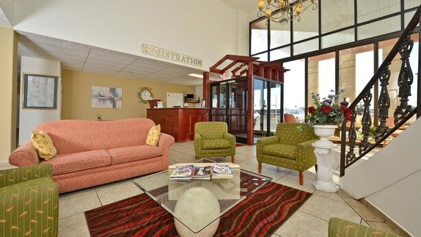 A hotel lobby with a registration desk, a staircase, and seating areas.