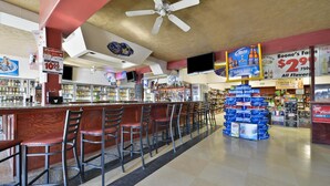 A bar area with multiple stools, a ceiling fan, and a display of beer crates.
