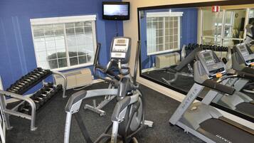 A gym with treadmills, an elliptical, and dumbbells.